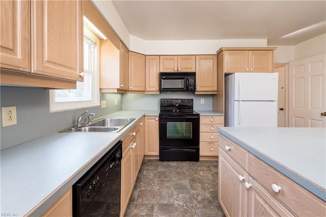 kitchen featuring light brown cabinetry, light countertops, stone finish floor, black appliances, and a sink