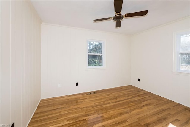 unfurnished room with ceiling fan, wood finished floors, visible vents, and ornamental molding