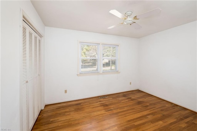 unfurnished bedroom featuring a ceiling fan, visible vents, wood finished floors, and a closet