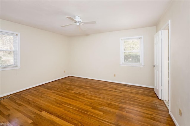 unfurnished room with visible vents, a ceiling fan, baseboards, and wood finished floors