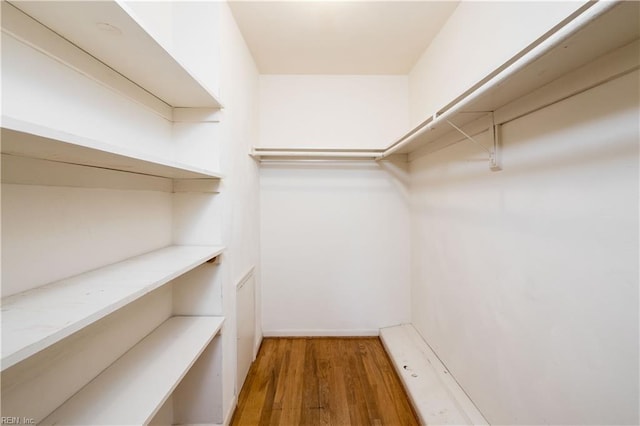 walk in closet with wood finished floors