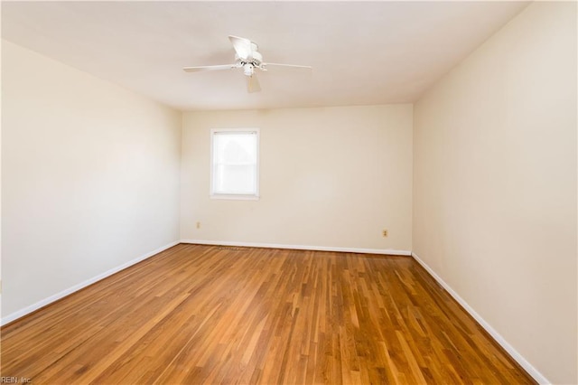 empty room featuring ceiling fan, baseboards, and wood finished floors