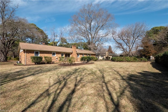 exterior space with a lawn, a chimney, and brick siding