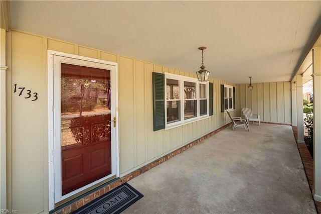 view of exterior entry featuring a porch and board and batten siding