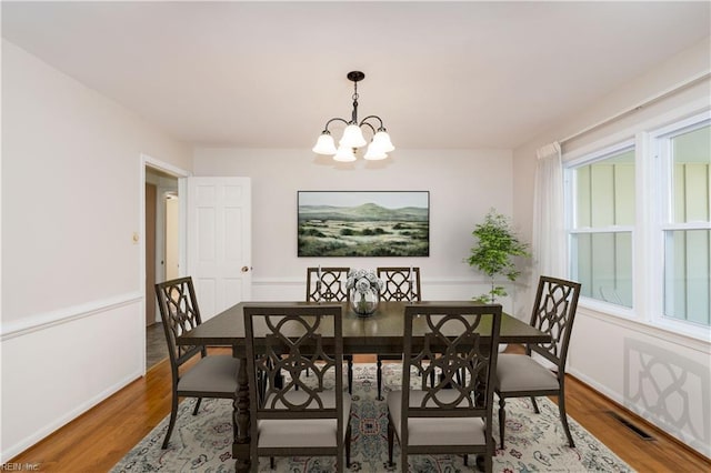 dining area with visible vents, an inviting chandelier, and wood finished floors