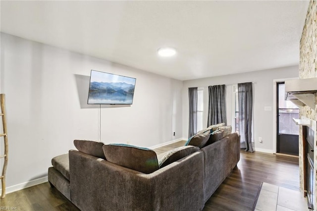 living area with a fireplace, baseboards, and wood finished floors