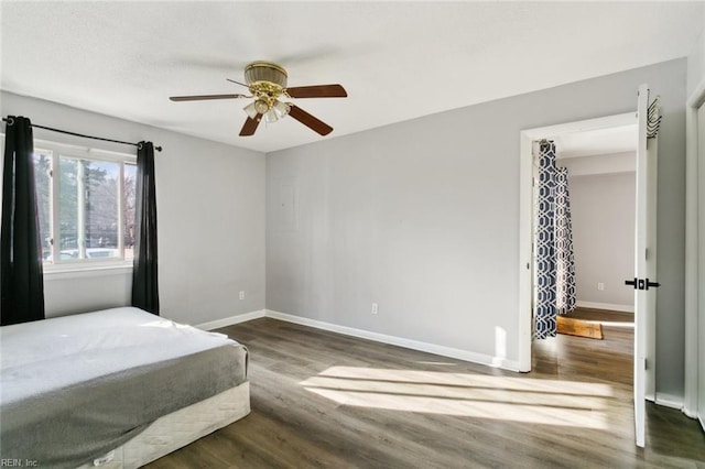 bedroom featuring a ceiling fan, baseboards, and wood finished floors