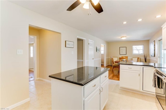 kitchen featuring recessed lighting, a kitchen island, white cabinetry, baseboards, and stainless steel range with electric stovetop