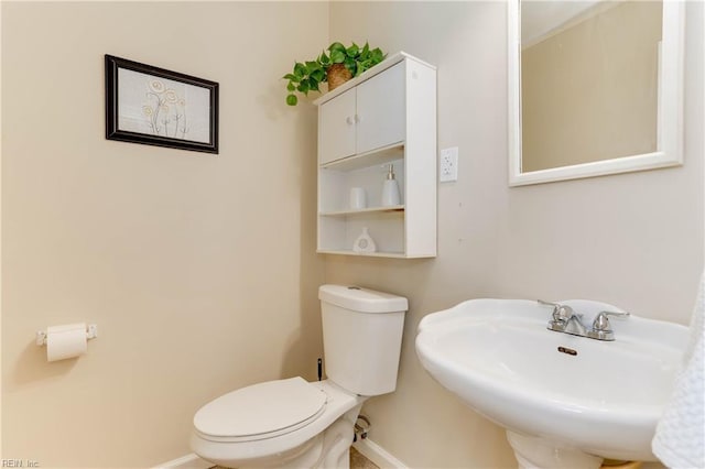 bathroom with baseboards, a sink, and toilet