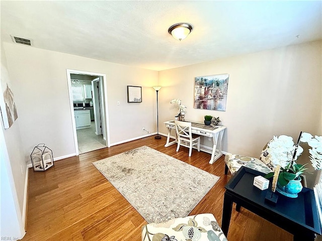 office area featuring visible vents, baseboards, and wood finished floors