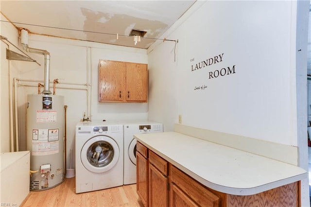 laundry area featuring gas water heater, cabinet space, light wood-style flooring, and washing machine and clothes dryer