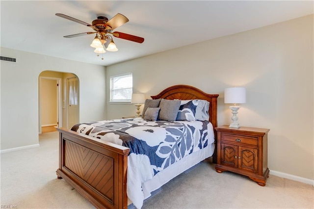 bedroom featuring light carpet, baseboards, visible vents, and arched walkways