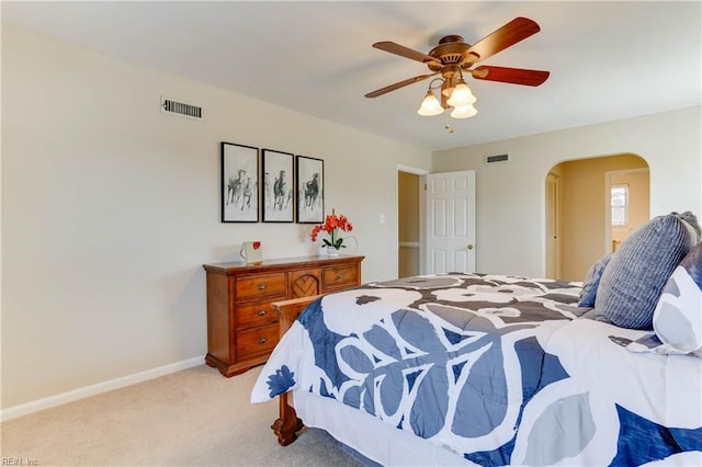 bedroom featuring arched walkways, visible vents, light carpet, and baseboards