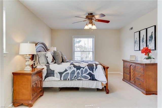 bedroom featuring baseboards, visible vents, ceiling fan, and light colored carpet