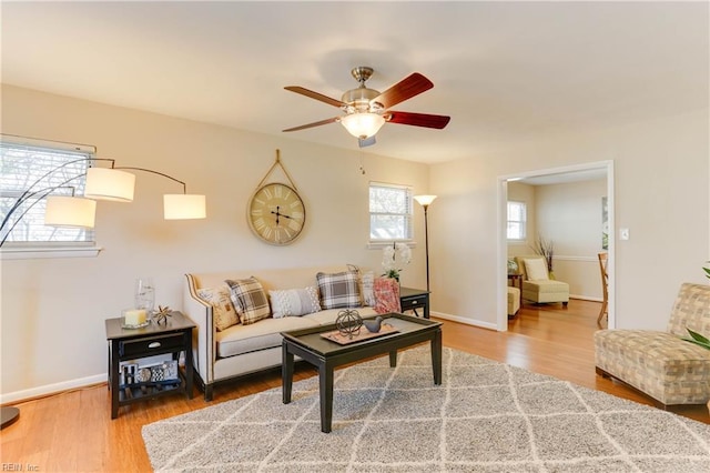 living room featuring a ceiling fan, baseboards, and wood finished floors