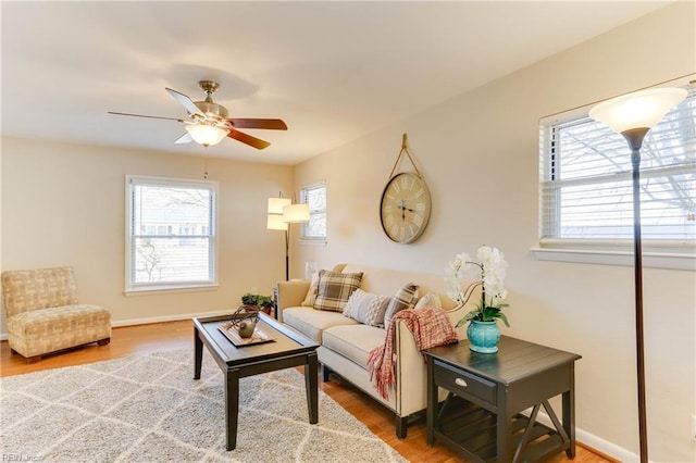 living room with wood finished floors, a ceiling fan, and baseboards