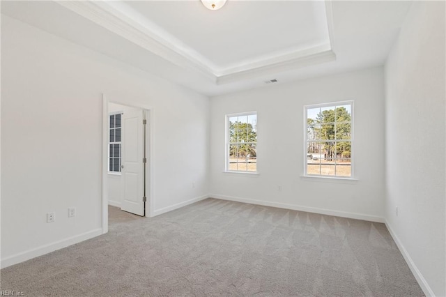 empty room with baseboards, visible vents, a tray ceiling, and carpet flooring