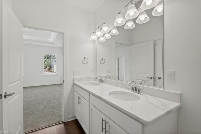 full bathroom with double vanity, baseboards, and a sink