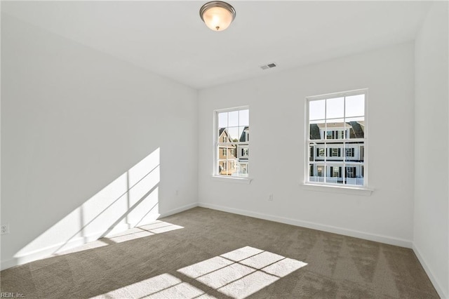 carpeted spare room featuring visible vents and baseboards