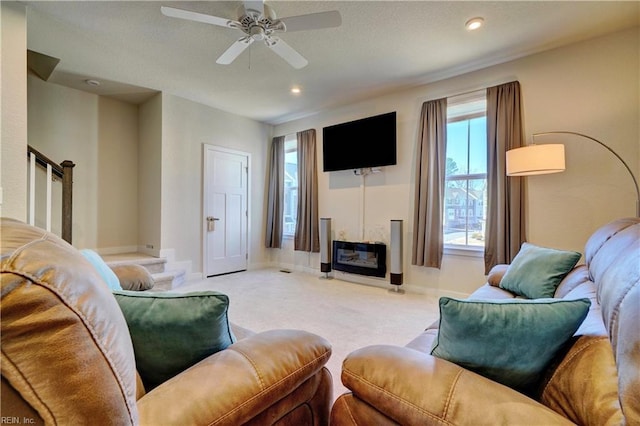 carpeted living area featuring recessed lighting, stairway, a glass covered fireplace, ceiling fan, and baseboards