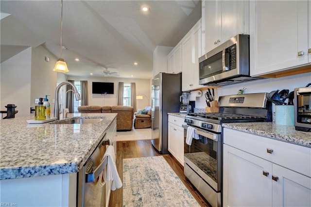 kitchen featuring dark wood-style flooring, a sink, white cabinetry, appliances with stainless steel finishes, and light stone countertops