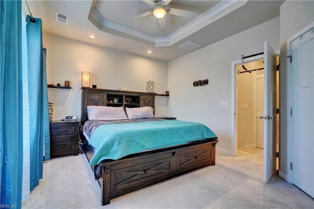 bedroom with a tray ceiling, recessed lighting, light colored carpet, visible vents, and baseboards