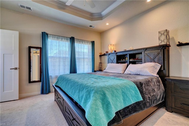 bedroom with a ceiling fan, light colored carpet, a raised ceiling, and visible vents