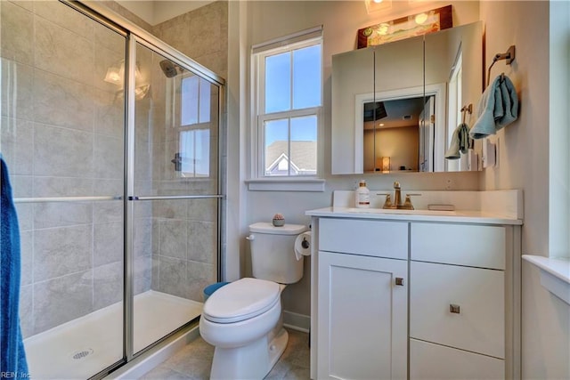 bathroom featuring toilet, a stall shower, baseboards, and vanity