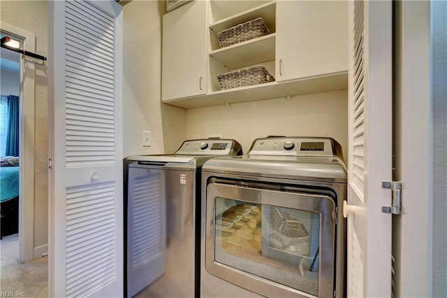 laundry area with cabinet space, washer and dryer, and a textured wall