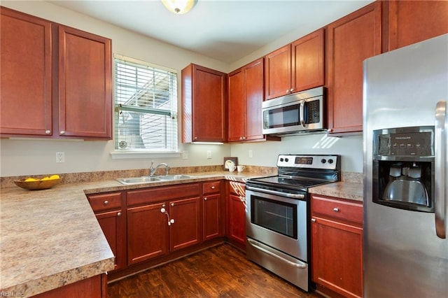 kitchen with appliances with stainless steel finishes, light countertops, dark wood-type flooring, and a sink