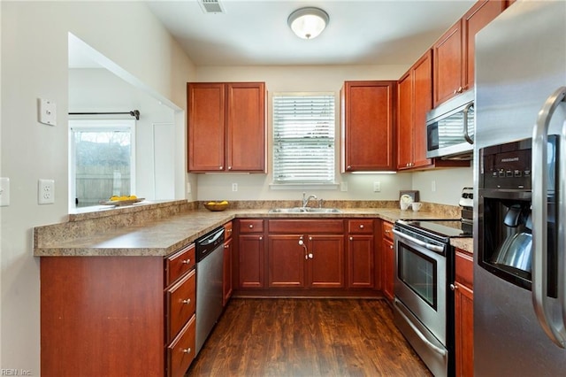 kitchen featuring dark wood-style flooring, visible vents, appliances with stainless steel finishes, a sink, and a peninsula