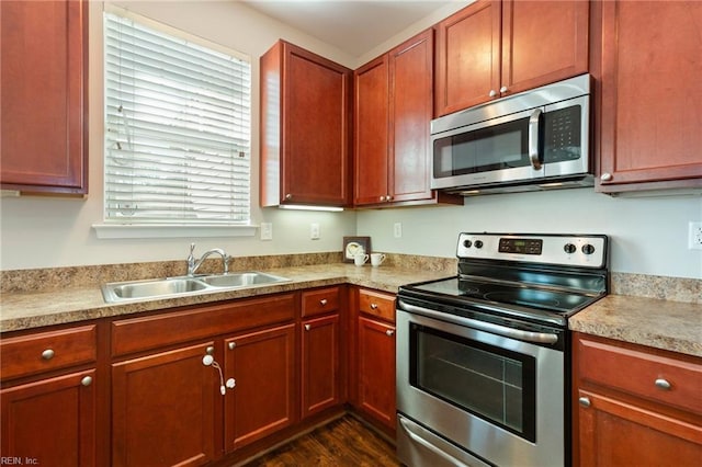 kitchen featuring stainless steel appliances, light countertops, a sink, and dark wood-style floors