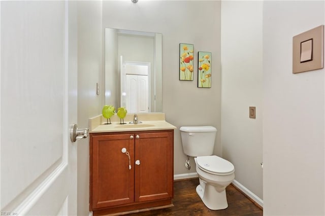 bathroom with wood finished floors, vanity, toilet, and baseboards