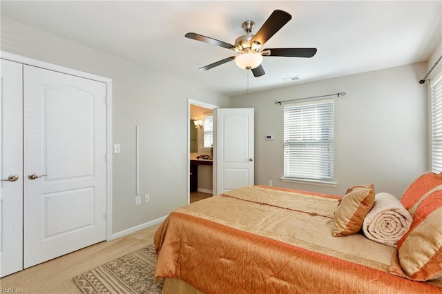 bedroom featuring ceiling fan, ensuite bathroom, light carpet, and baseboards