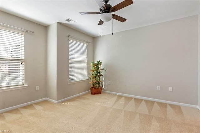 spare room with light carpet, ceiling fan, visible vents, and baseboards