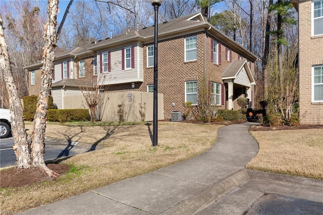 multi unit property featuring a front yard, central AC unit, and brick siding