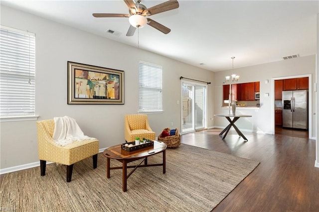 sitting room featuring dark wood-style floors, ceiling fan with notable chandelier, visible vents, and baseboards