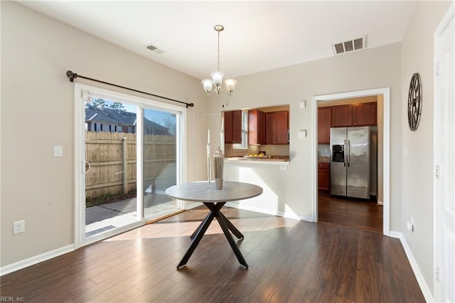 unfurnished dining area with dark wood-style flooring, visible vents, a notable chandelier, and baseboards