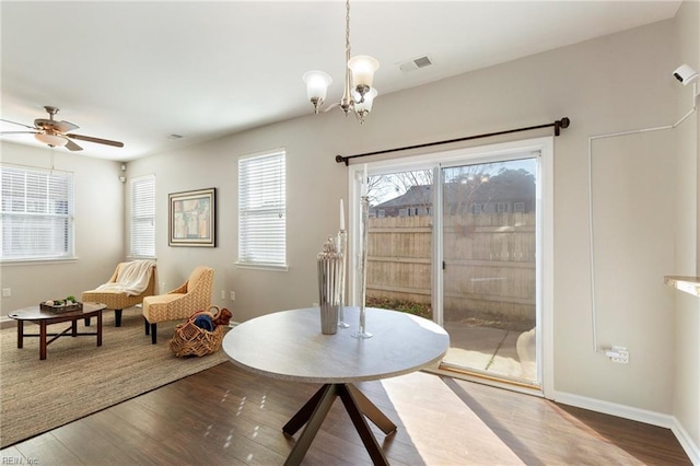 dining area with ceiling fan with notable chandelier, wood finished floors, visible vents, and baseboards