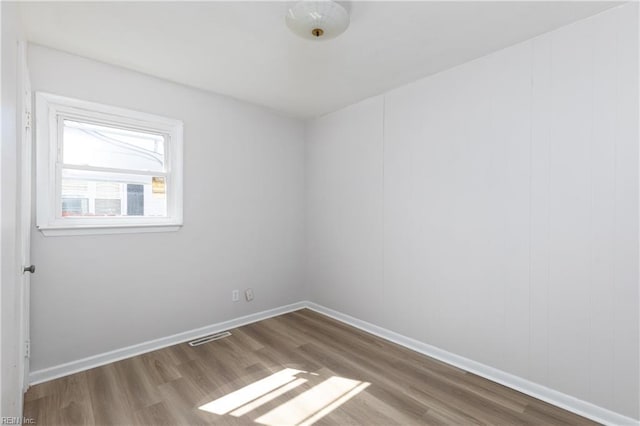 unfurnished room with visible vents, baseboards, and wood finished floors