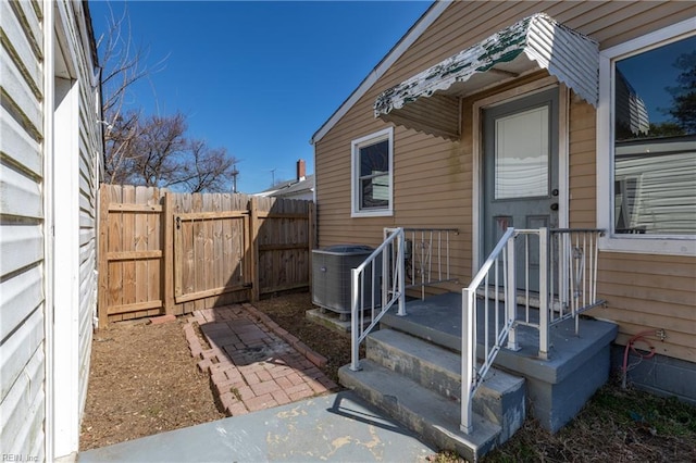 view of exterior entry featuring fence and cooling unit