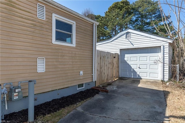 detached garage with concrete driveway and fence