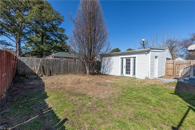 view of yard featuring an outbuilding, french doors, and a fenced backyard