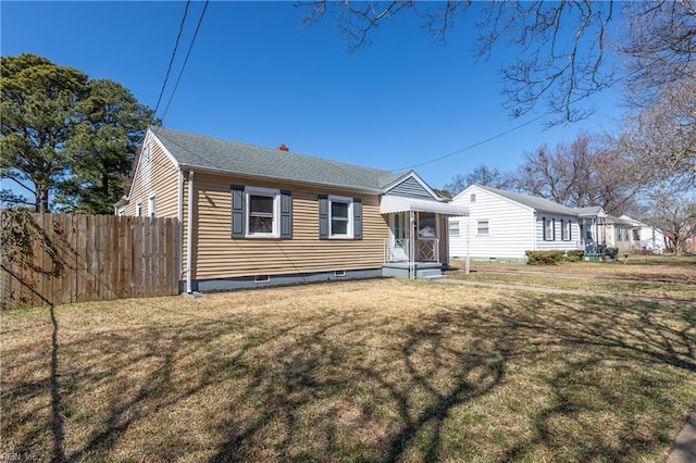 view of front facade with roof with shingles, fence, and a front yard