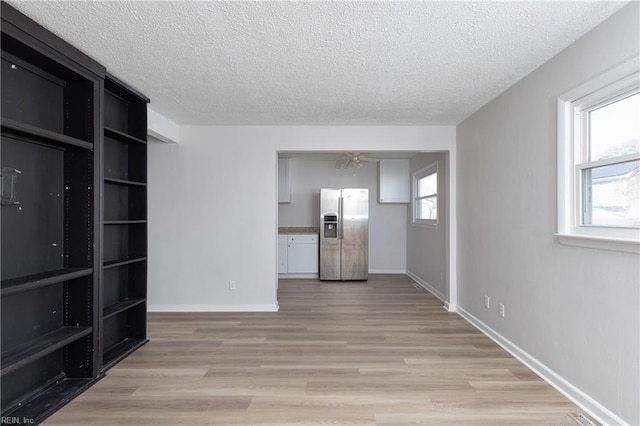 unfurnished living room featuring light wood-style floors, plenty of natural light, and a textured ceiling