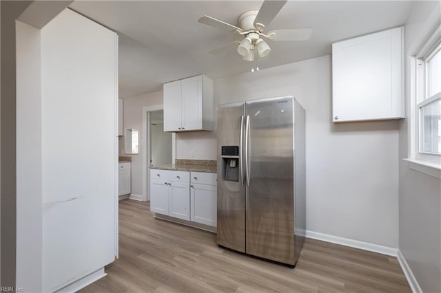 kitchen featuring a ceiling fan, white cabinets, light wood-type flooring, stainless steel fridge, and baseboards