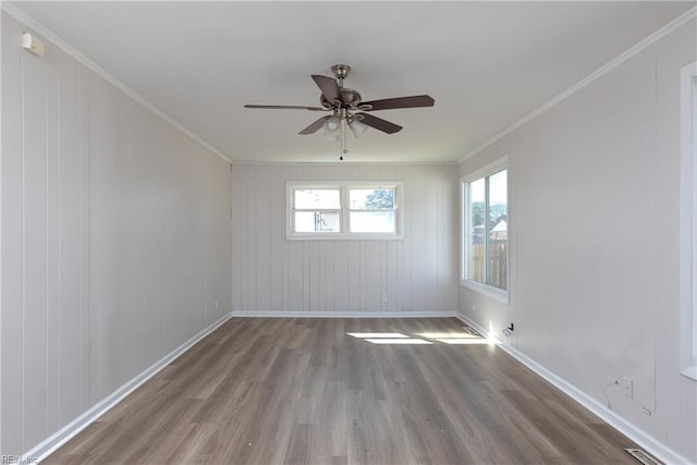 empty room with ceiling fan, ornamental molding, wood finished floors, and baseboards