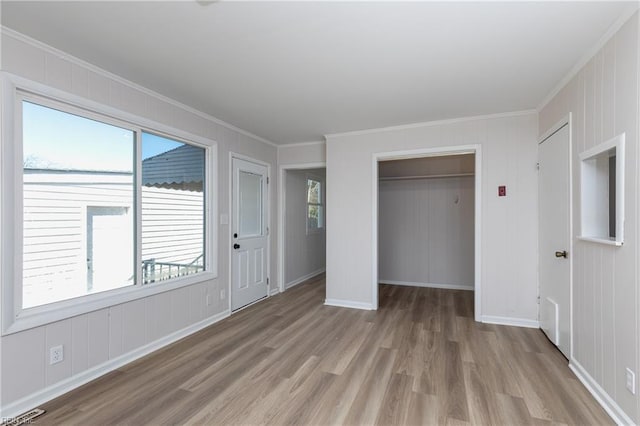 unfurnished bedroom with light wood-style floors, visible vents, crown molding, and baseboards