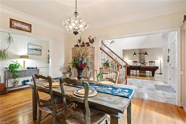 dining space with ornamental molding, light wood finished floors, stairway, and an inviting chandelier