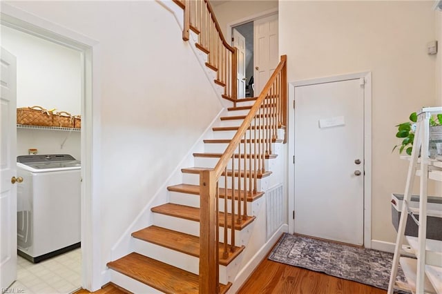 staircase with wood finished floors and washer / dryer